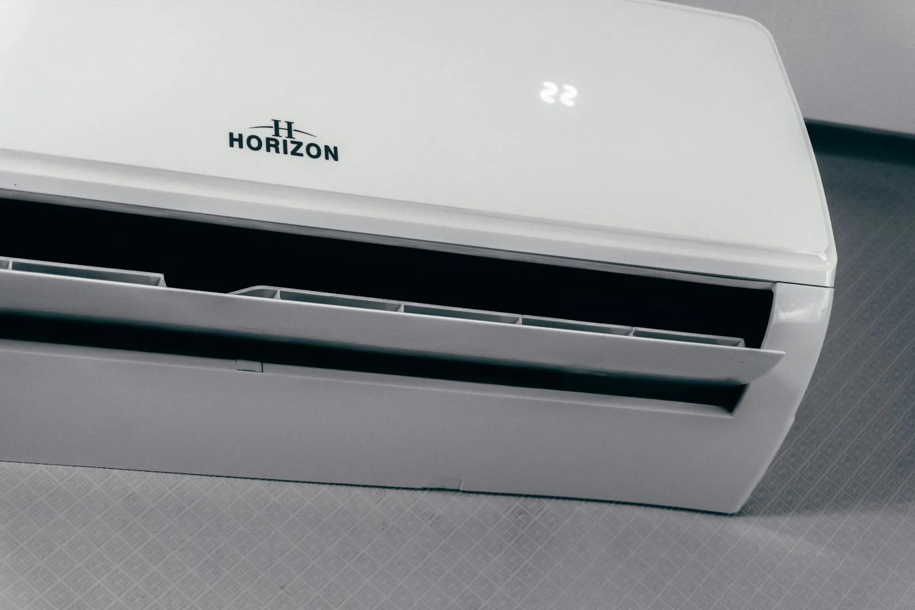 A white split AC on a wall, its display showing 22 degrees